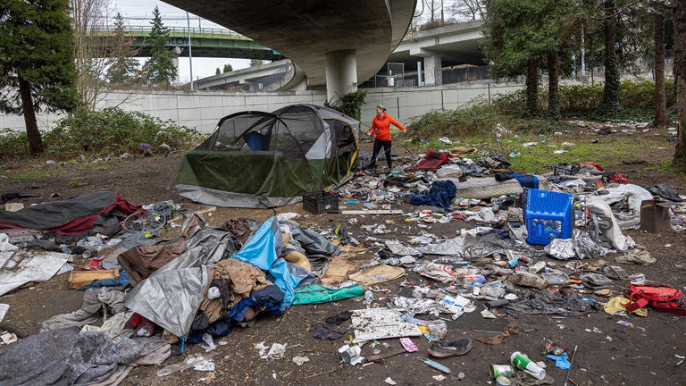 Andrea Suarez dismantles a tent at a homeless encampment with garbage piled around in Seattle, Washington, on March 13, 2022. Suarez is the executive director of We Heart Seattle, a nonprofit that organizes trash cleanups across the city amid rising homelessness during the COVID-19 pandemic. Getty Images