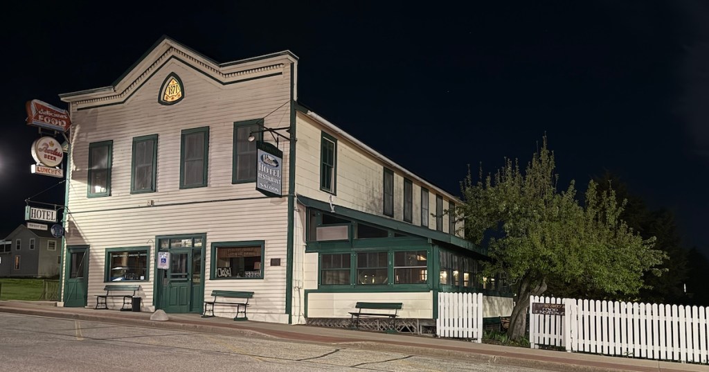 Night view of the historic Hotel Trempealeau building with white siding and green trim in Wisconsin.
