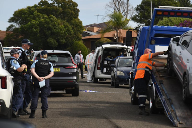 The silver sedan being towed as police watch on at the scene on Juliet Close.