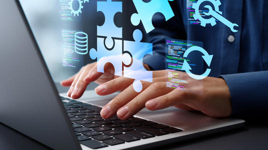 A person typing on their laptop with multiple icons floating over it