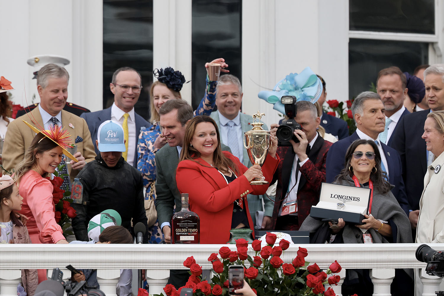 Cherie DeVaux smiles while holding a trophy surrounded by other people.