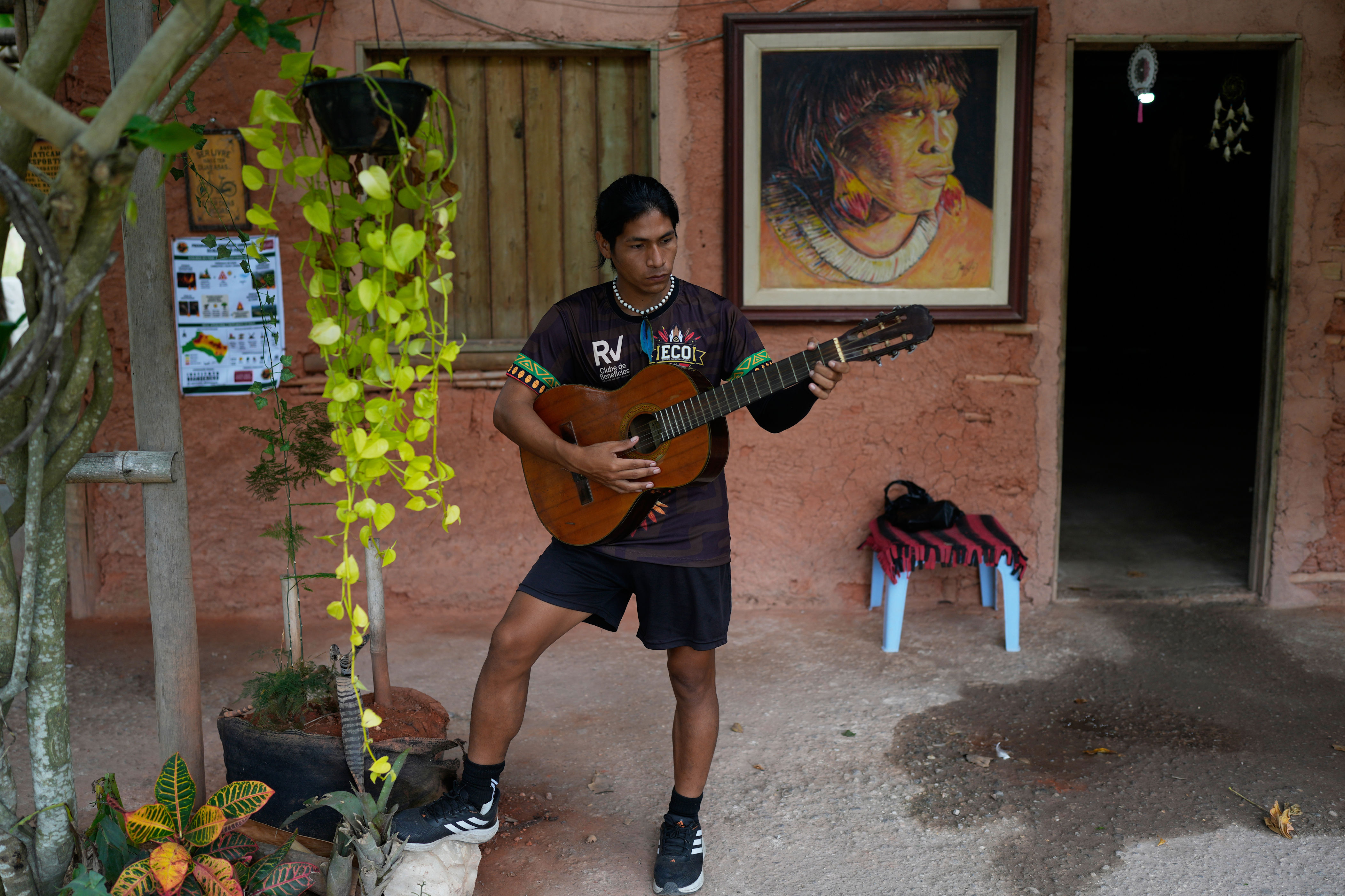 Edilson Nunes da Silva, a player of Originarios, a new soccer team in Rio's fifth division made up exclusively of Indigenous players, plays the guitar at his home in Mata Verde Bonita village in Marica, Brazil, Tuesday, April 28, 2026. (AP Photo/Silvia Izquierdo)