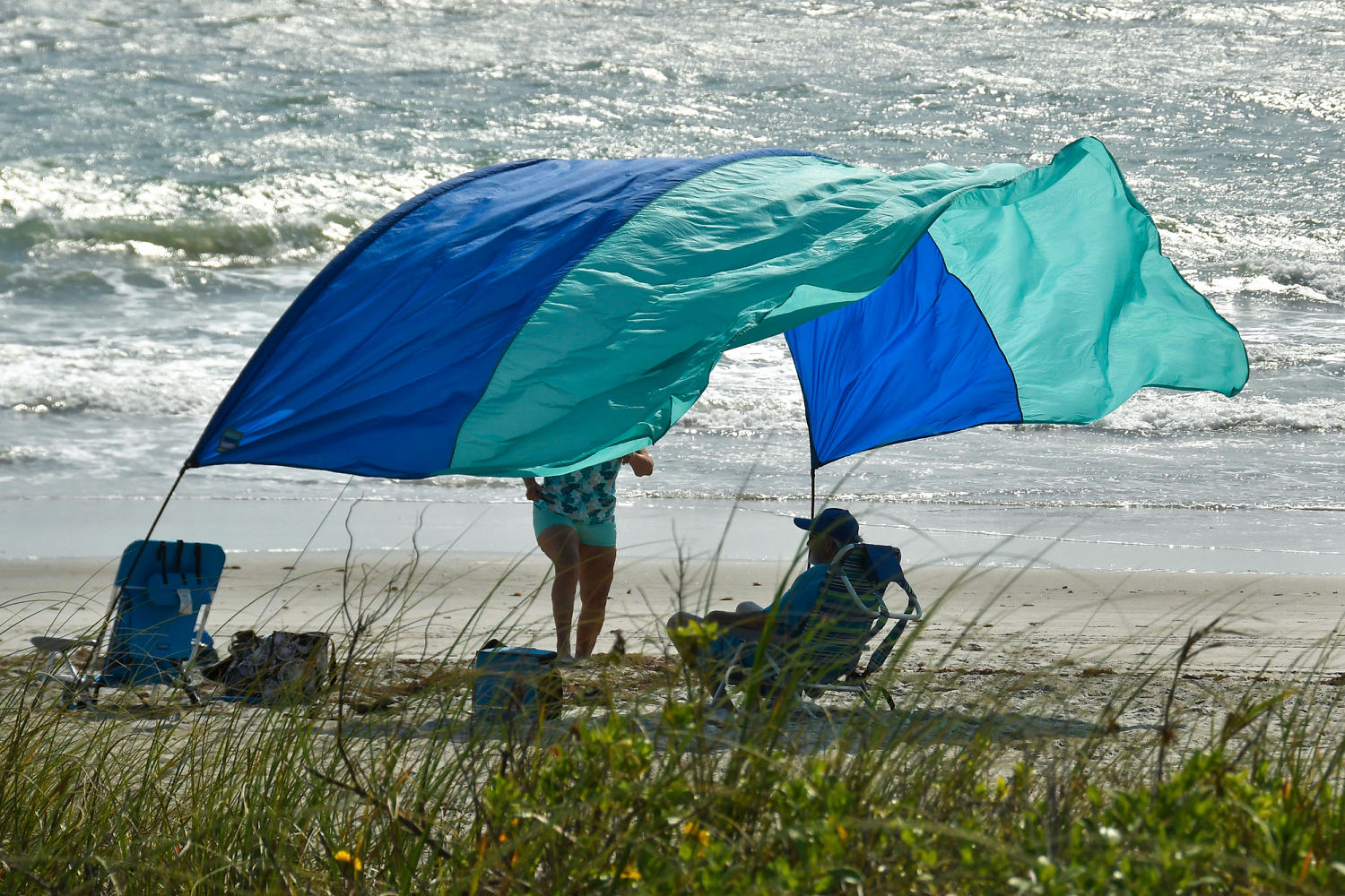 Photo shows a beachgoers sun canopy flapping in the strong winds at Tables Beach