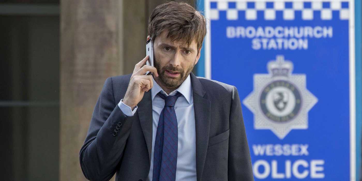 DI Alec Hardy (David Tennant) stands outside a police station on his phone in Broadchurch Season 3