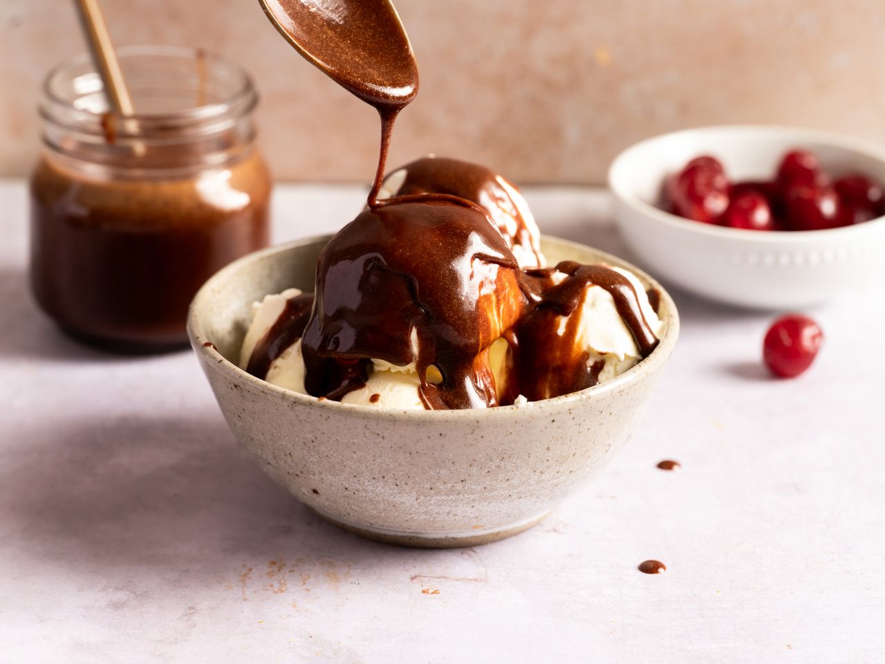 Chocolate sauce being drizzled over vanilla ice cream.
