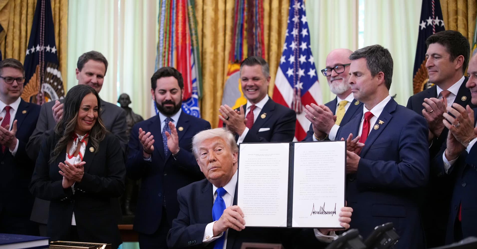 President Donald Trump holds up an executive order during an event in the Oval Office of the White House on April 30, 2026. Trump signed an order to expand retirement account access for workers.