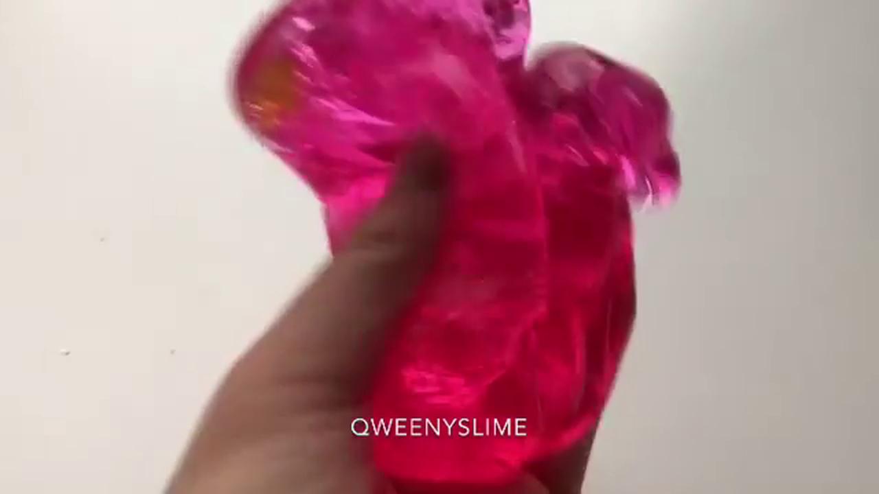 Poking and pressing clear pink jelly slime in jar creating glossy ...