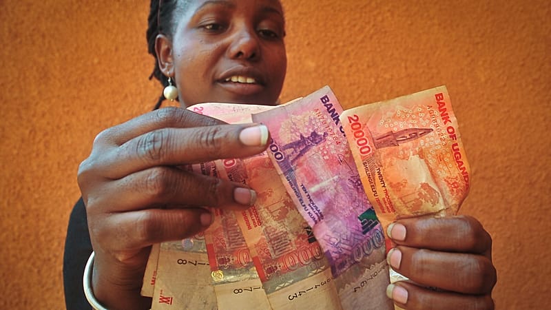 Une femme d'affaires ougandaise qui vend des céréales compte des billets de shilling ougandais à Kampala, en Ouganda, le 27 février 2014