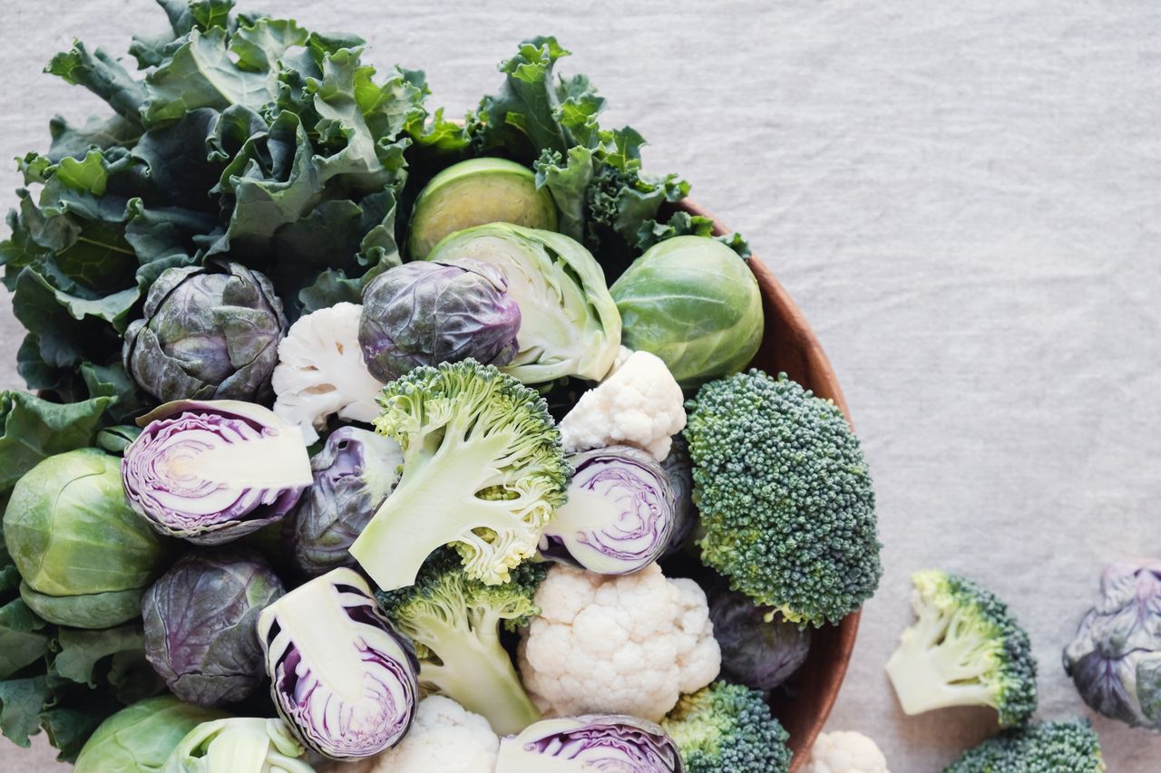A bowl filled with various fresh vegetables like broccoli cauliflower Brussels sprouts and kale