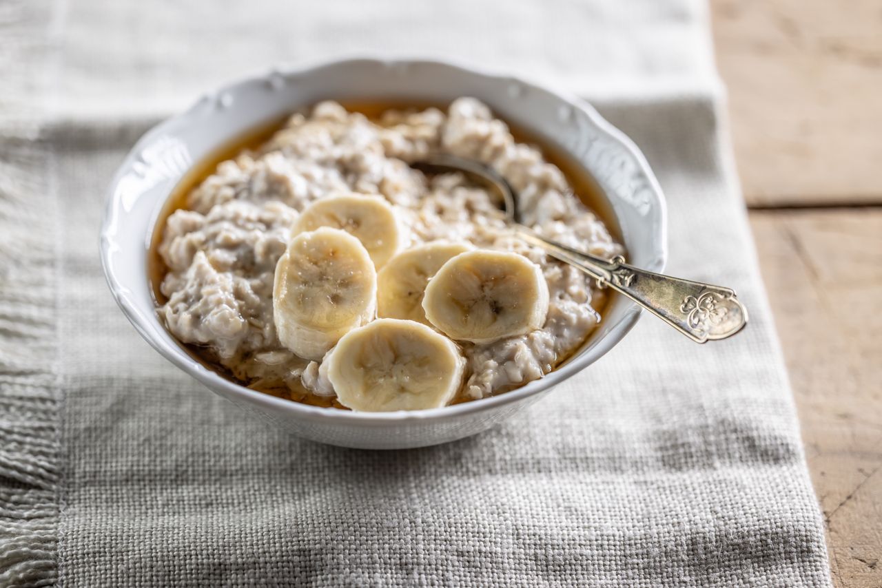 Bowl of oatmeal topped with banana slices and a spoon