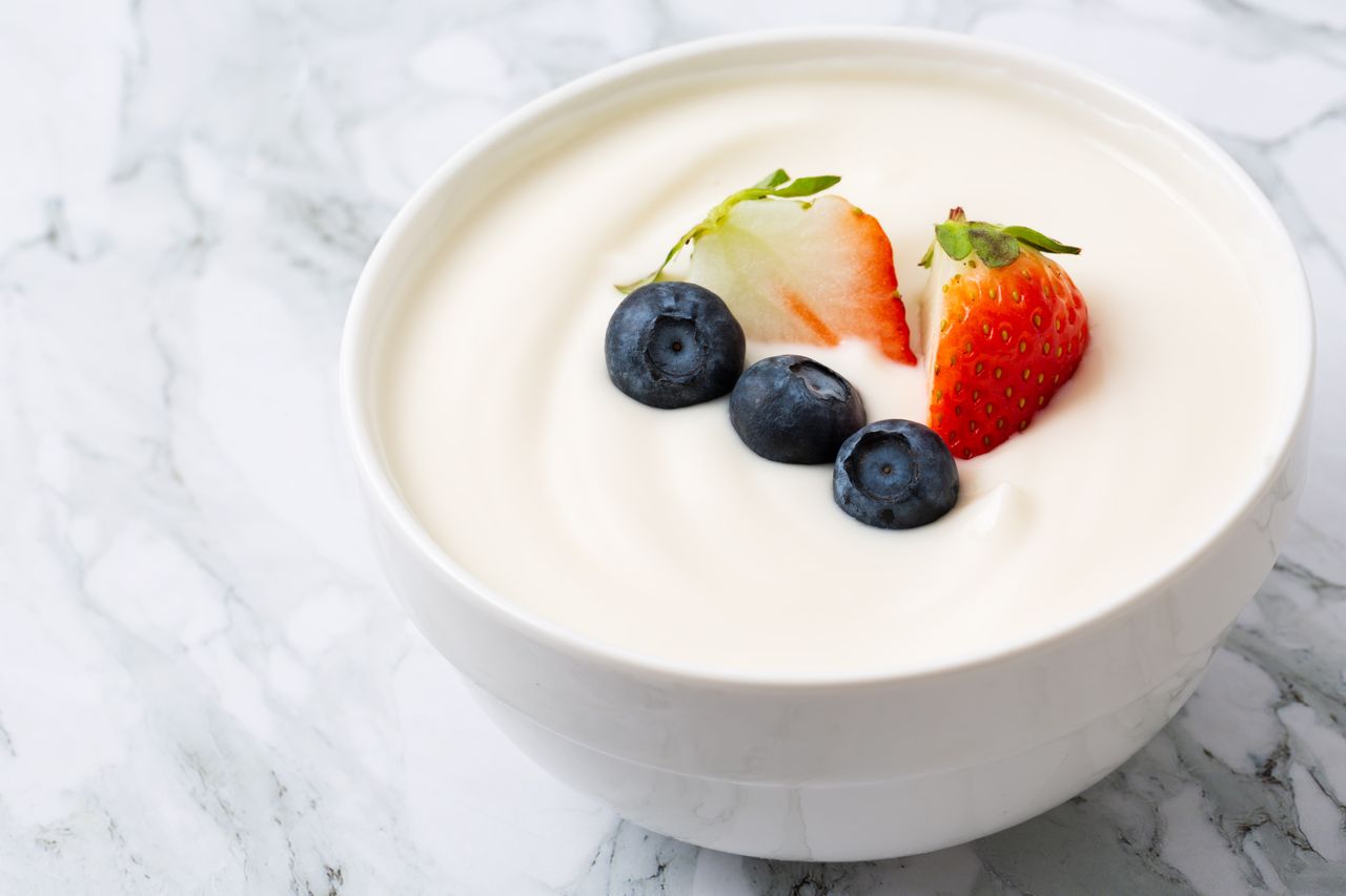 A bowl of yogurt topped with blueberries and a strawberry