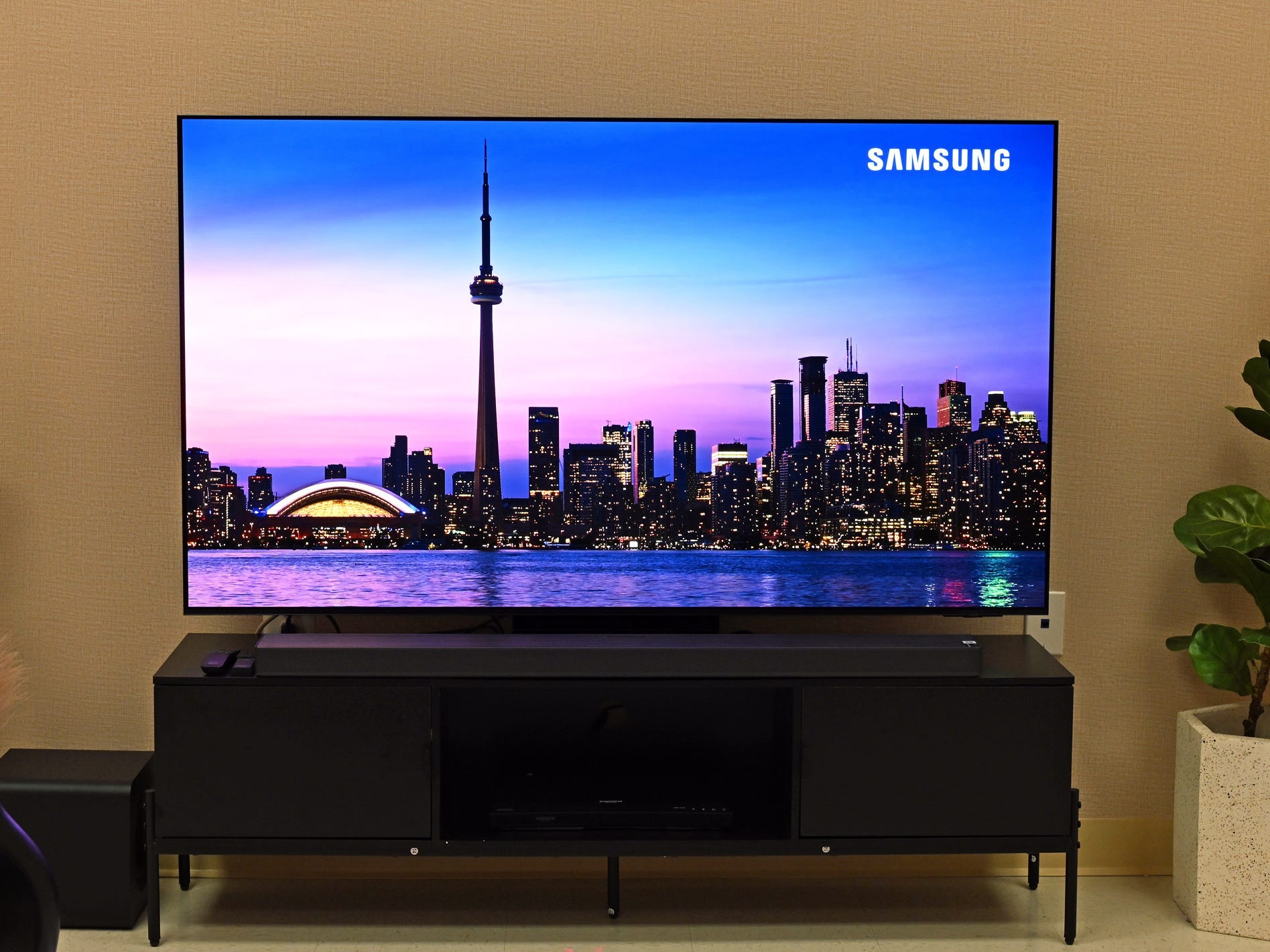 A Samsung S95F TV displaying a video of a cityscape at night.