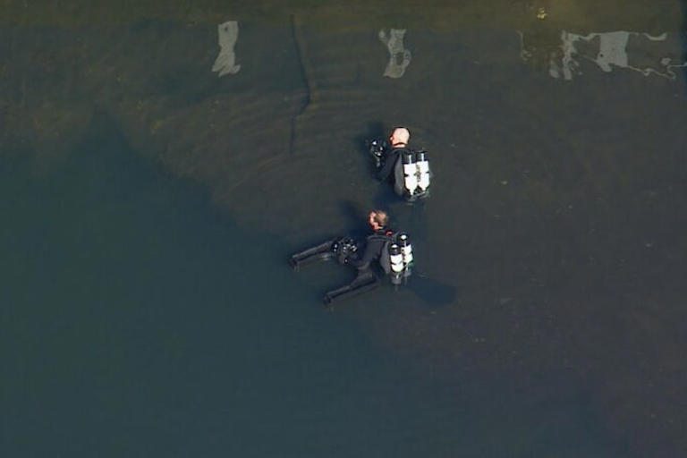Police divers in the Hacking River after a fatal crash in the Royal National Park.