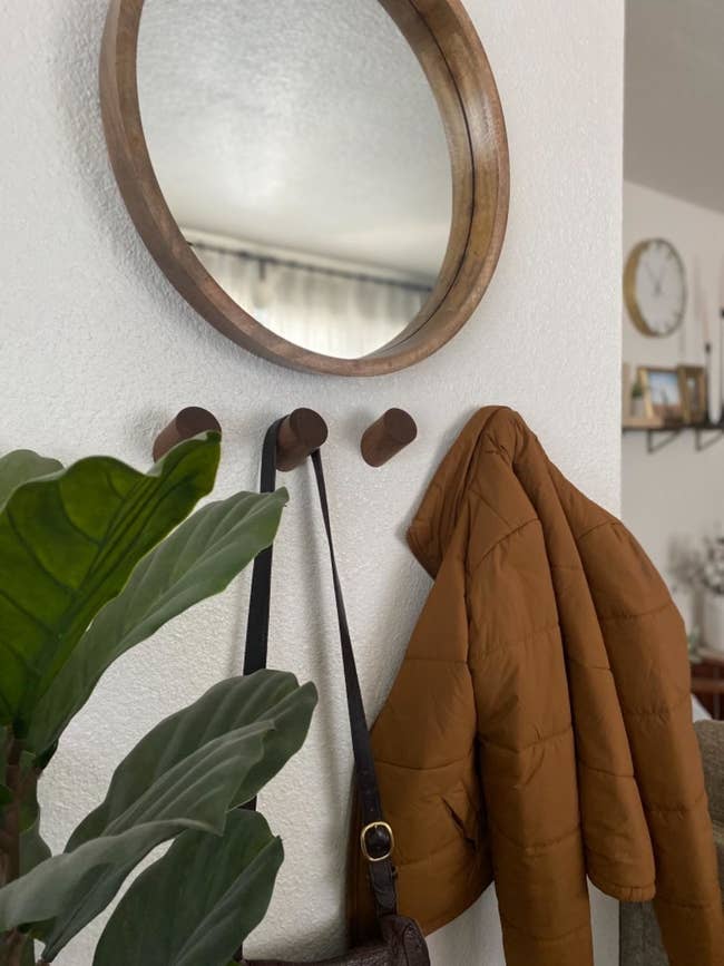 four wooden hooks with a bag and a jacket on two