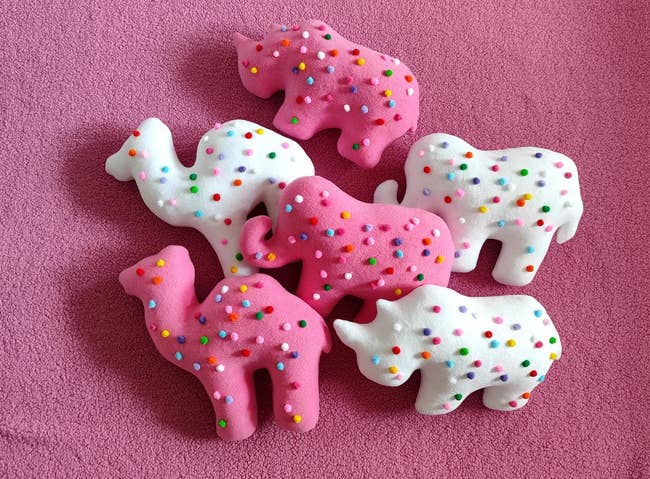Toy animals with sprinkles: two camels, two elephants, two rhinoceroses, placed on a textured surface