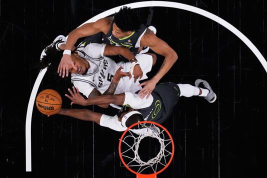 San Antonio Spurs guard Stephon Castle (5) is blocked by fouled by Minnesota Timberwolves guard Mike Conley (10) and guard Terrence Shannon Jr. (1) during the first half in Game 2 of a second-round NBA playoffs basketball series in San Antonio, Wednesday, May 6, 2026. (AP Photo/Eric Gay)