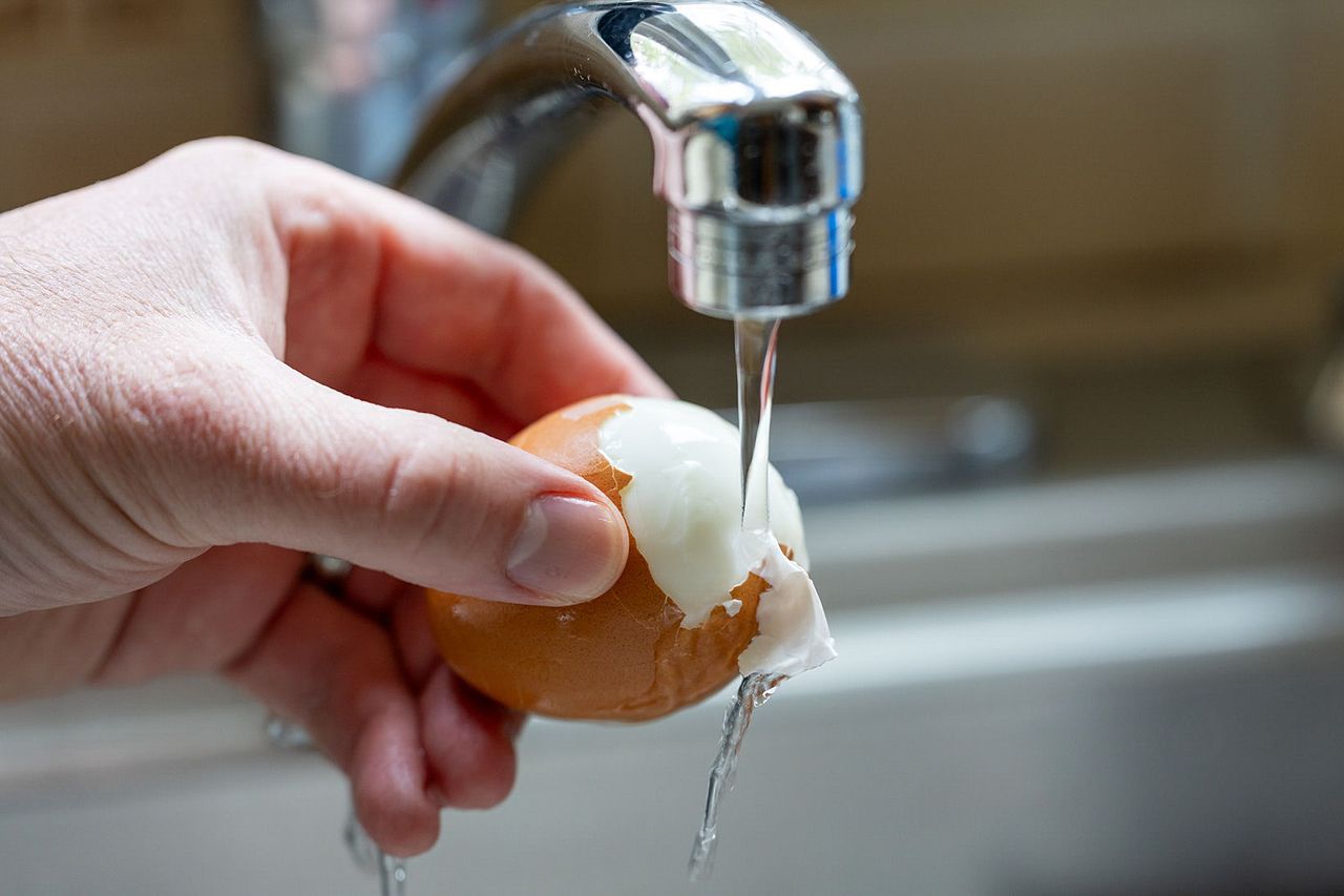 Peeling eggs under running water.