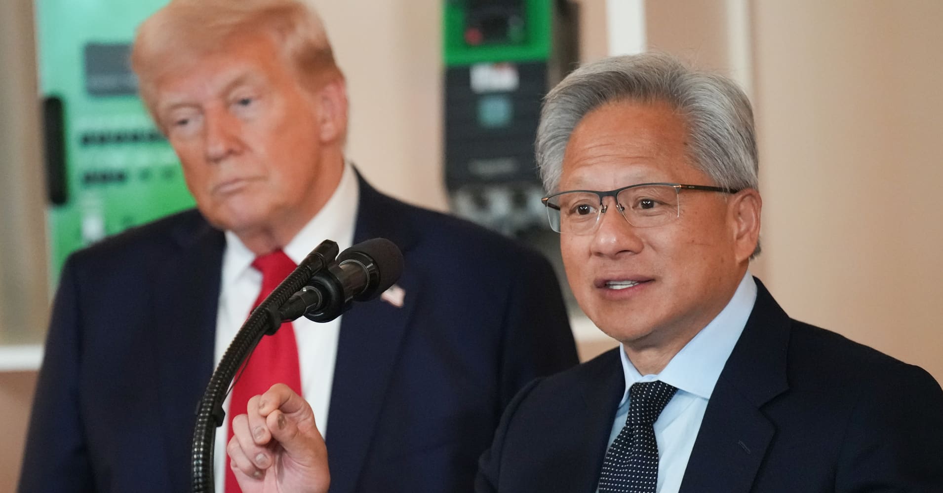 U.S. President Donald Trump (L) listens as Nvidia CEO Jensen Huang speaks in the Cross Hall of the White House during an event on