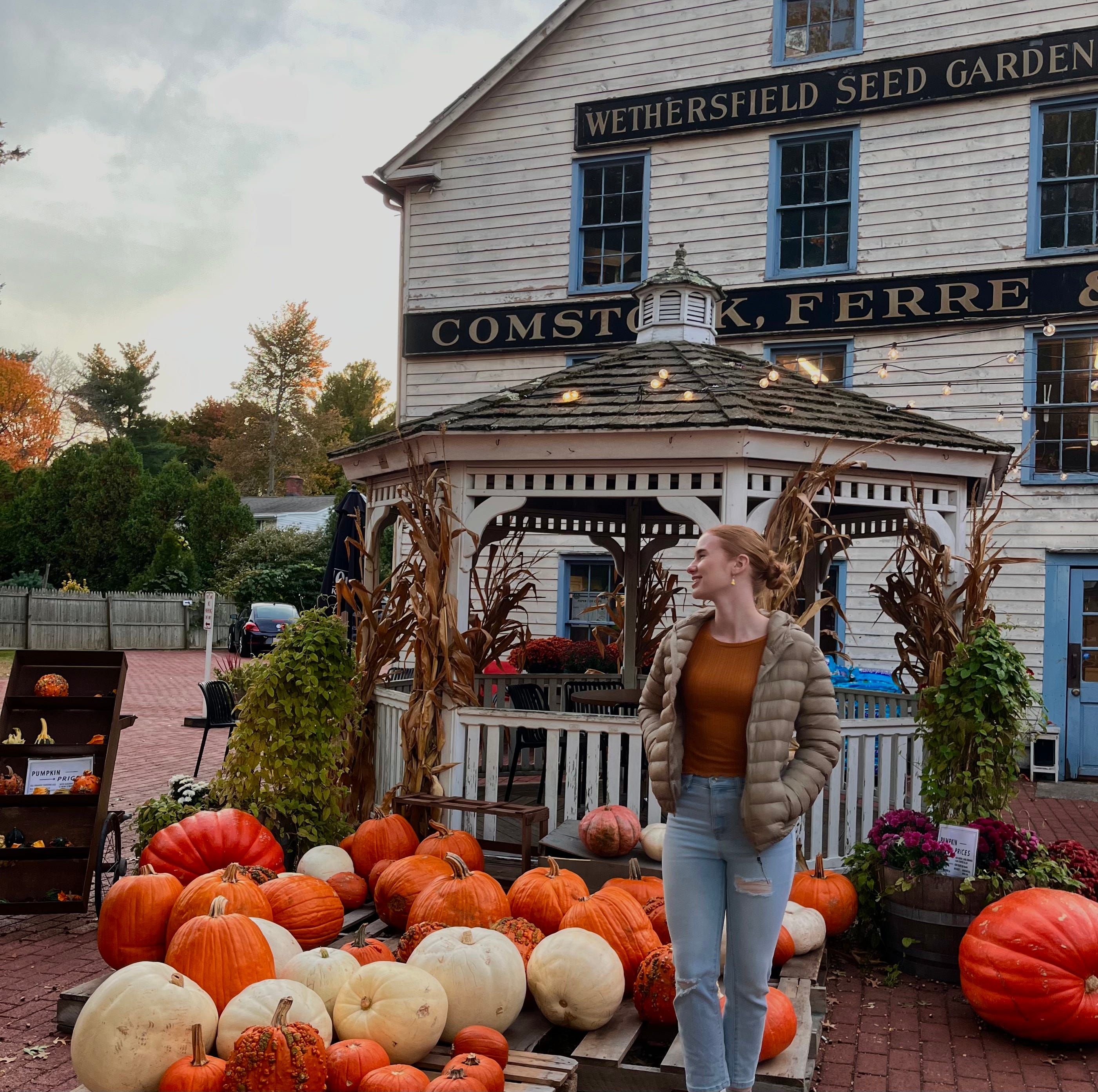 Woman smiling next to gazebo, pumpkins in Wethersfield, CT