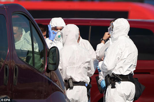 A potential hantavirus infection in Illinois unrelated to the outbreak on the MV Hondius cruise ship is being investigated (Pictured: Staff wearing PPE suits prepare for the transfer of passengers from the ship at the Port of Granadilla de Abona on Tenerife Island on Monday)