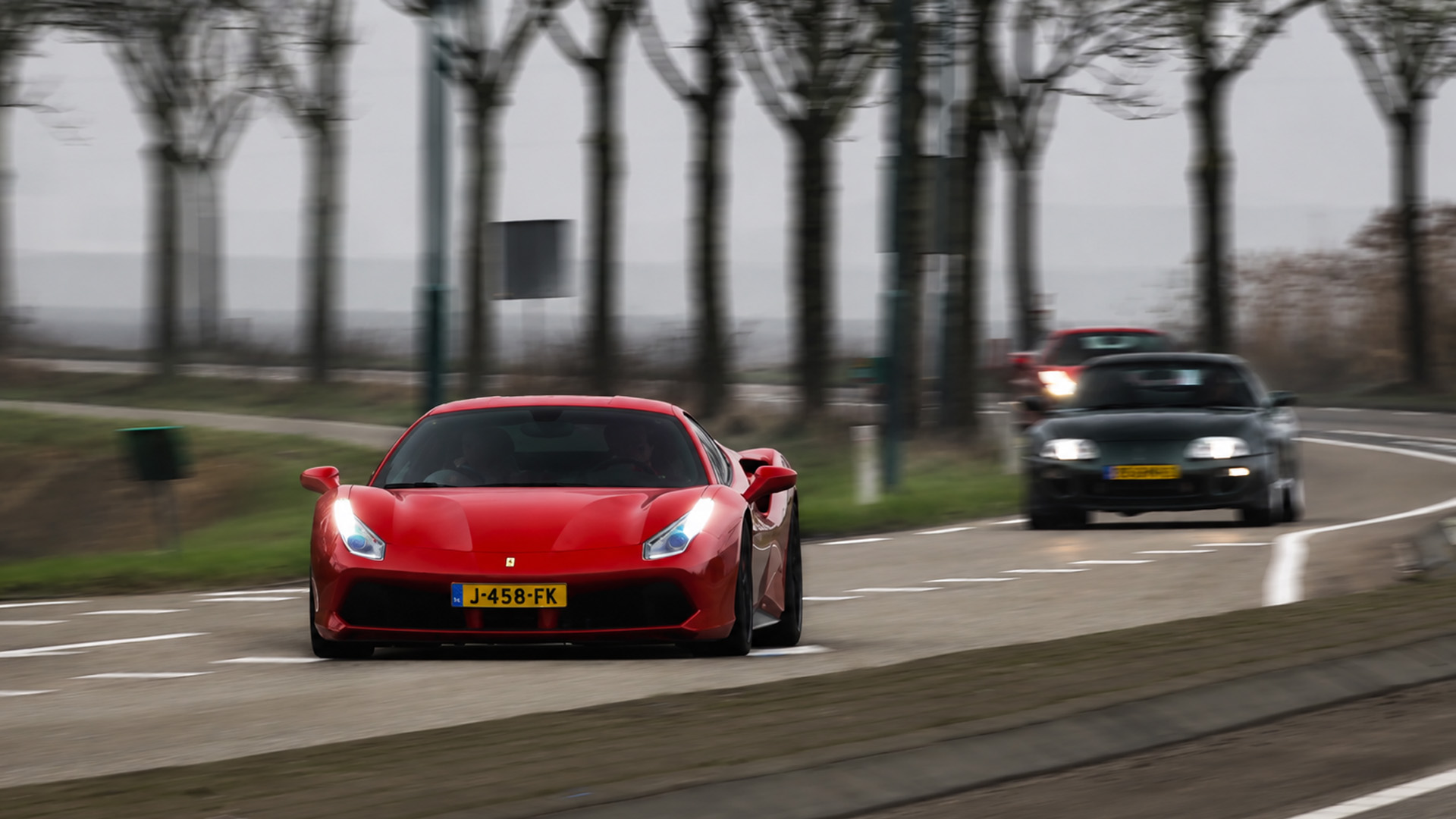 Une Toyota Supra poursuit une Ferrari 488 GTB sur route ouverte