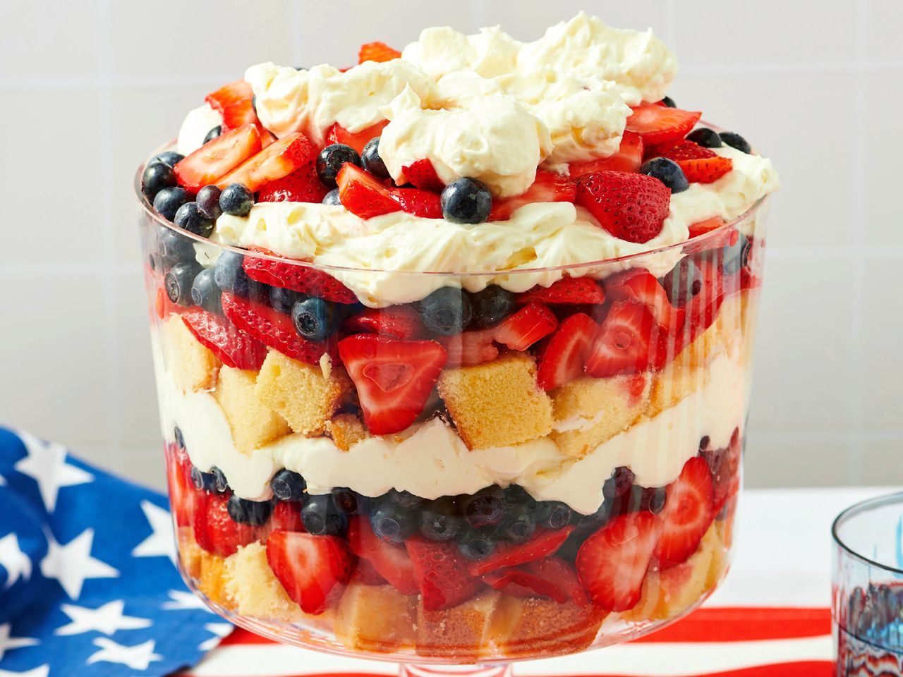 A layered dessert with cream strawberries blueberries and cake in a glass dish