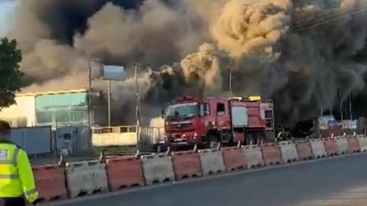 Roadside fire sends dense smoke column high above the street