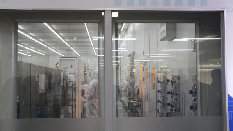 Interior de una sala limpia de fabricación de semiconductores, donde operarios trabajan bajo condiciones extremas de control ambiental necesarias para producir los chips avanzados de los que depende la economía global.