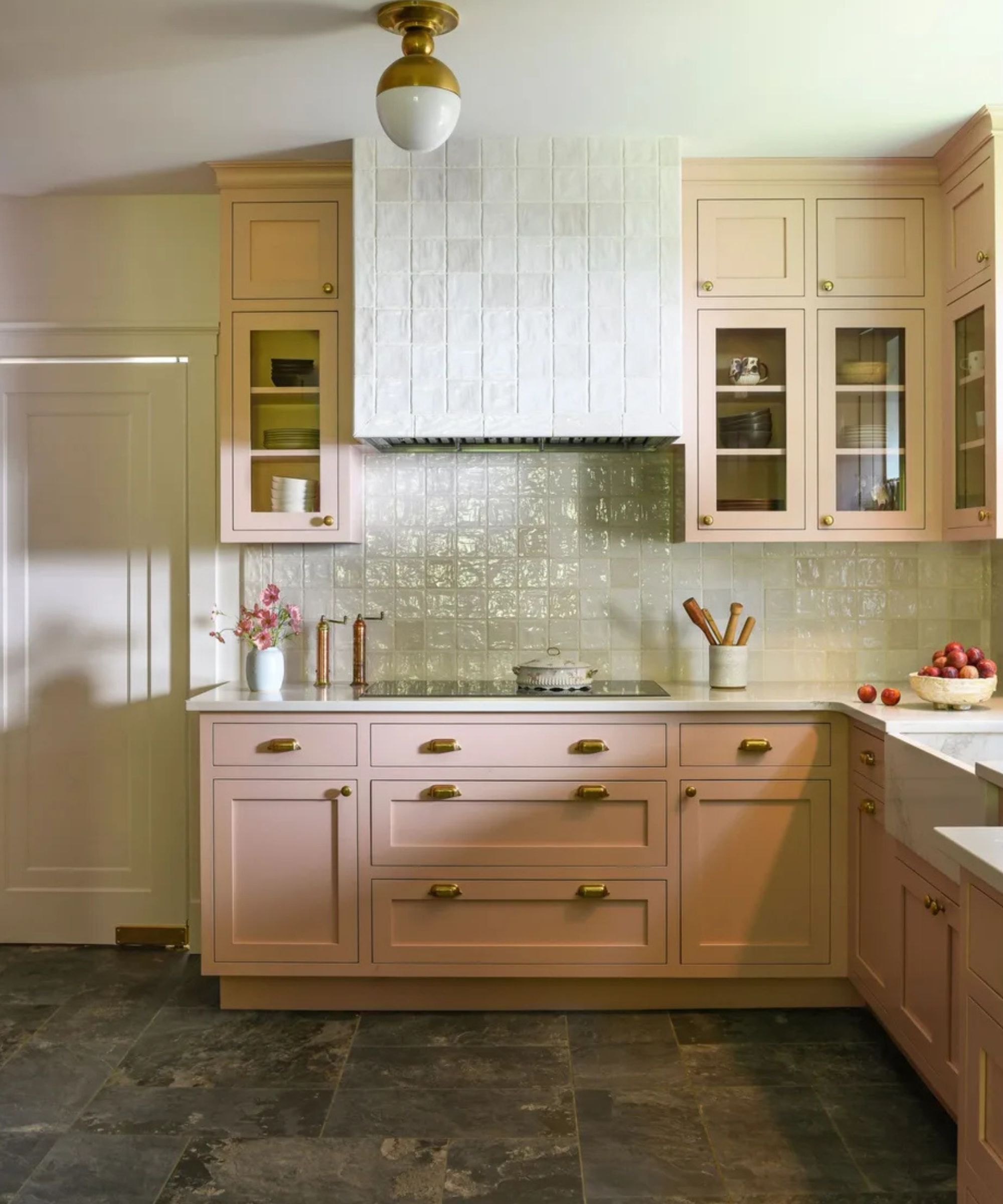 A kitchen with pink cabinets and glazed backsplashtiles
