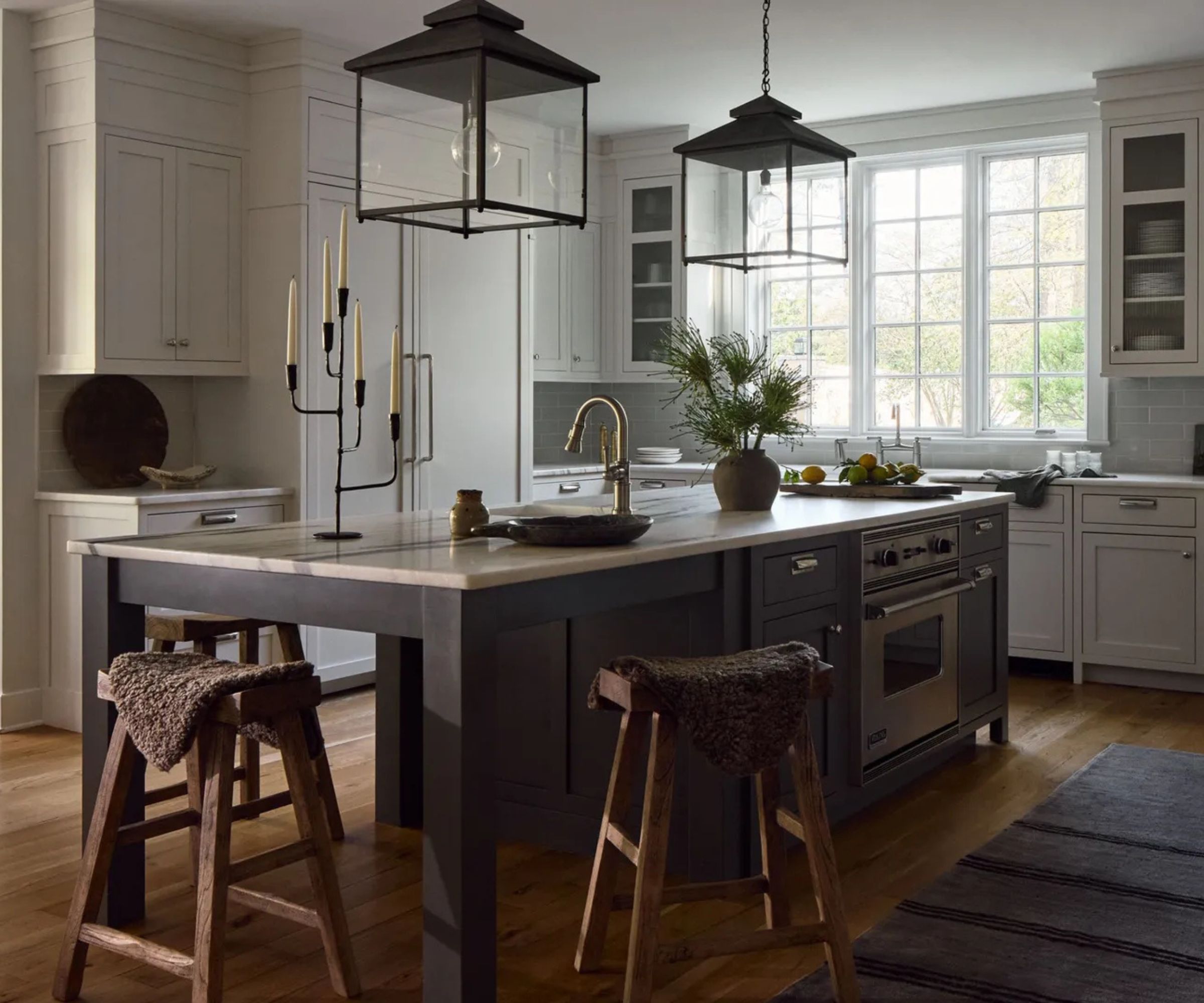A modern traditional kitchen with white cabinets, and dark wood island, and a mix of hardware styles