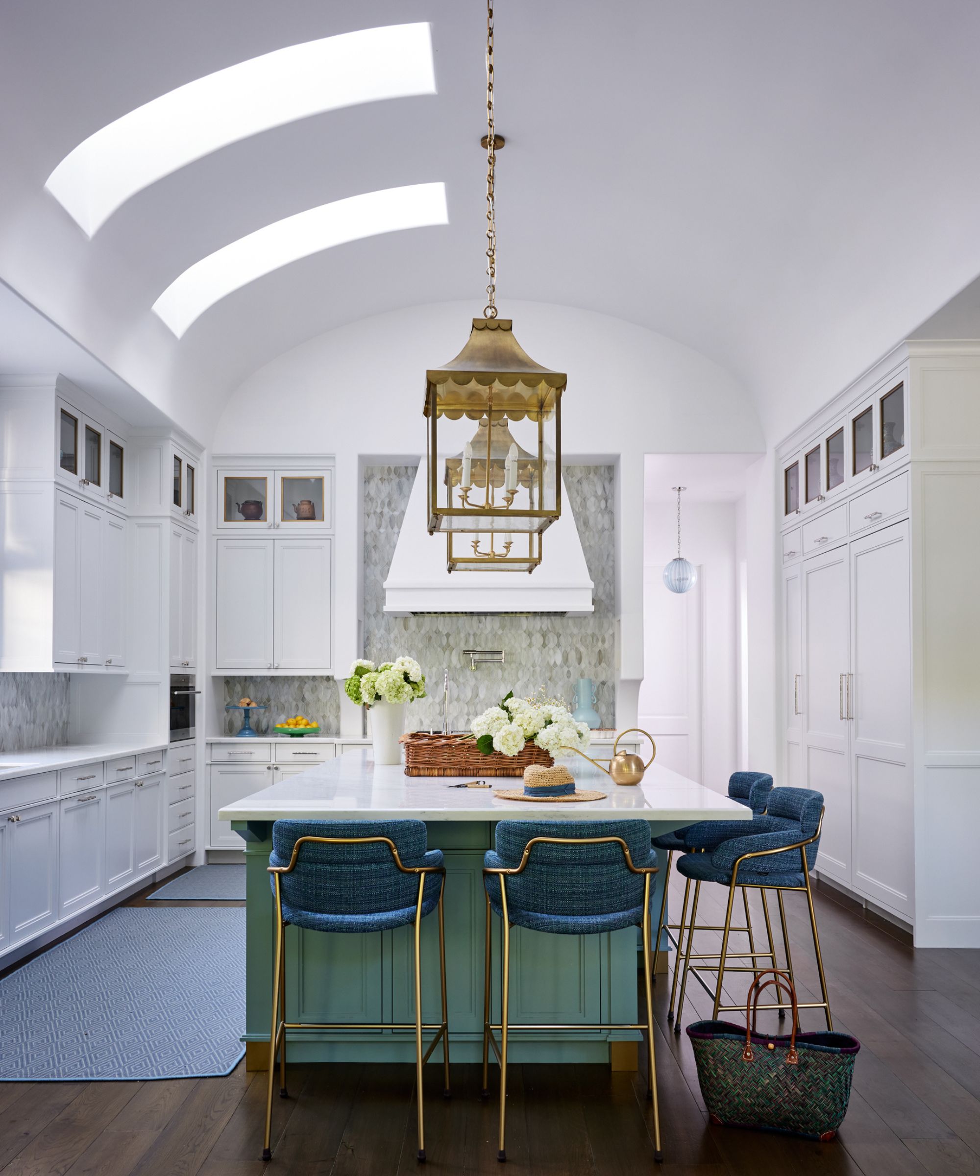 A white kitchen with a green island and tall domed ceilings, emphasised by two skylights