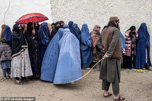 According to the UN Assistance Mission in Afghanistan , the regulation includes a section addressing girls who reach puberty while already married. Pictured: A Taliban security personnel stands guard as Afghan burqa-clad women wait in queue