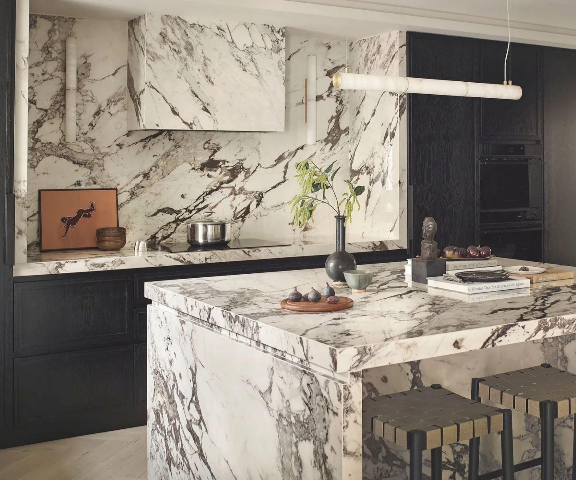 A large kitchen with dark wood cabinets, a fully marble island, and the same marble carried over the countertops and backsplash