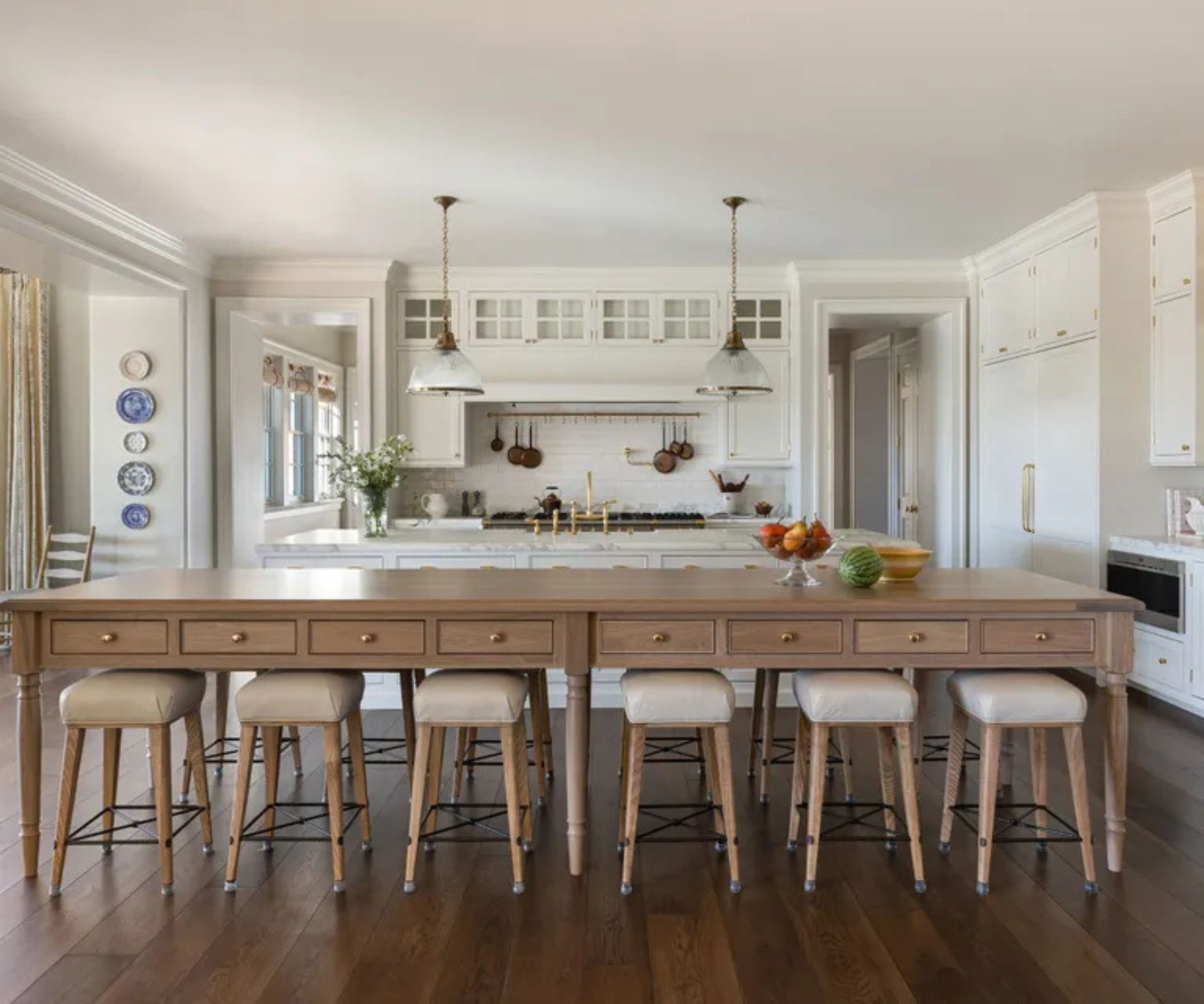 A white kitchen with an extra long wooden island for seating