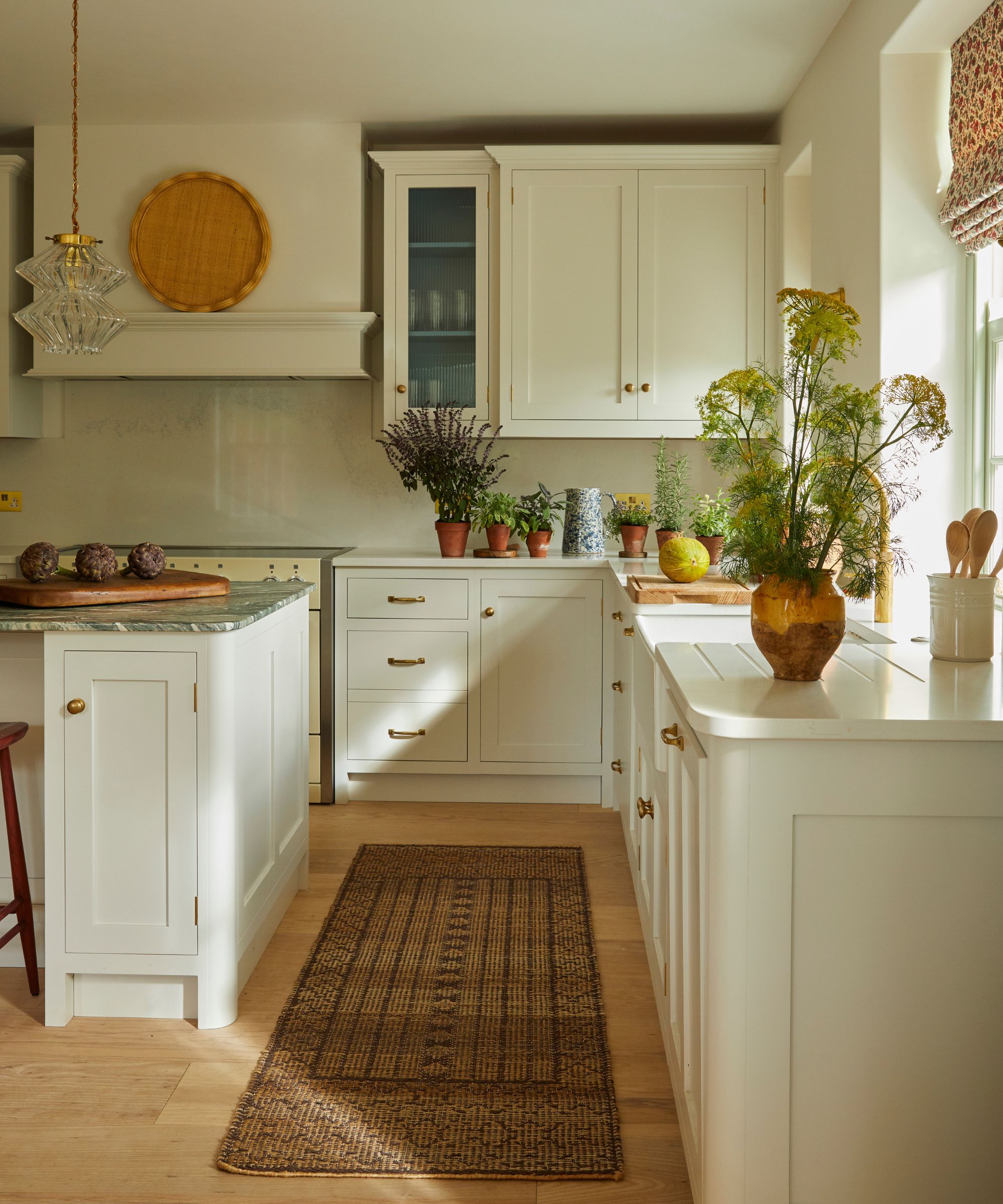 A coastal kitchen with warm white cabinets and a vintage runner featuring rusty red tones