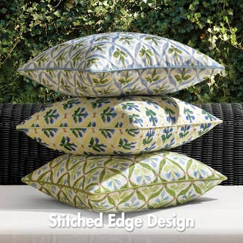 Three decorative pillows with leaf patterns are stacked on a wicker bench, labeled