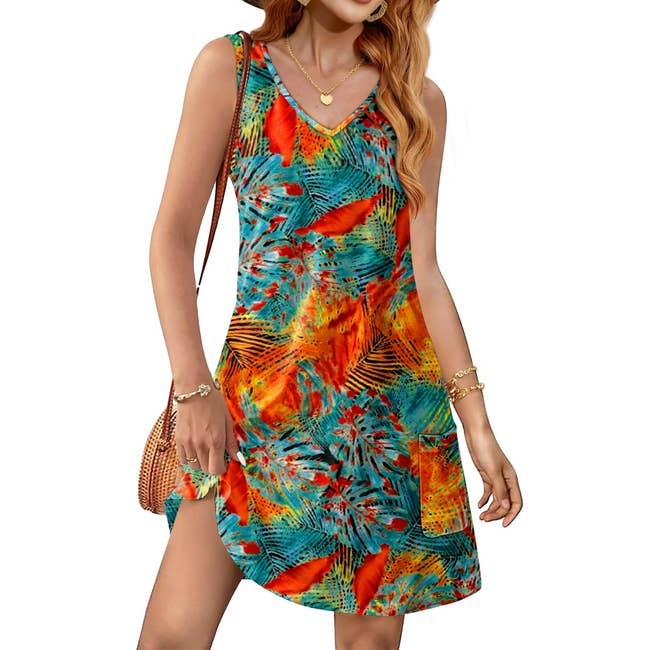 Model wearing a sleeveless, vibrant patterned summer dress with side slit