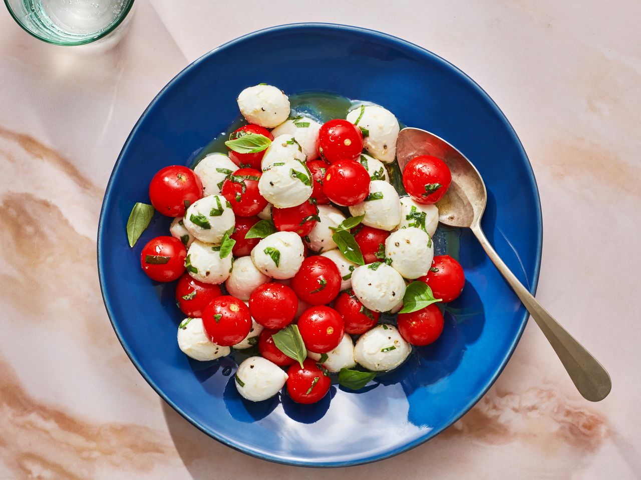 Marinated mozzarella, cherry tomato, and basil salad in a blue dish.