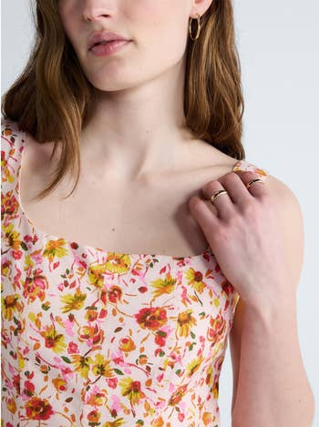 Person in a floral dress with their hand touching a shoulder, displaying a ring