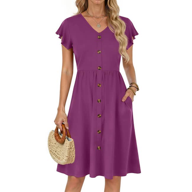 Person wearing a knee-length button-down dress with short sleeves, holding a straw handbag