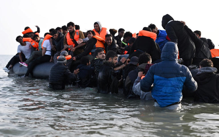 Migrants clamber over a dinghy at Gravelines near Calais on Saturday in preparation for the crossing to Britain - Dylan Martinez