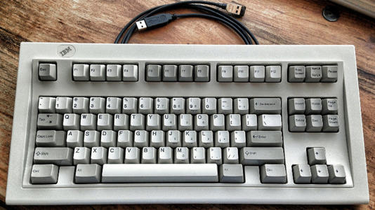 A gray IBM Model M keyboard on a table.