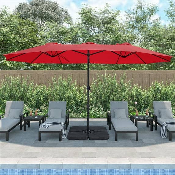 Poolside setup with a large red patio umbrella, four gray lounge chairs, and a garden backdrop