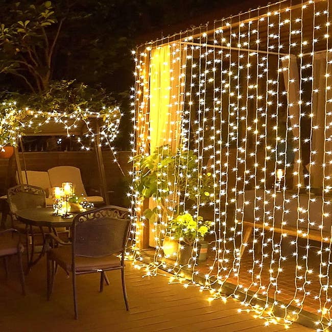 Outdoor patio with string lights draped around a gazebo and over a seating area, creating a cozy, illuminated space at night