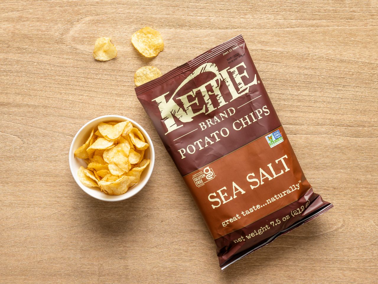 A bag of Kettle Brand sea salt potato chips with a small bowl of chips