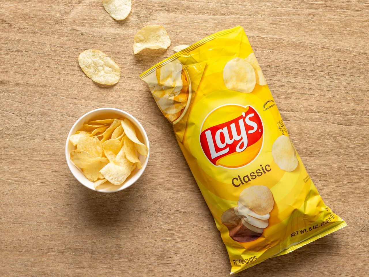 A bag of Lay's Classic potato chips with a small bowl of chips