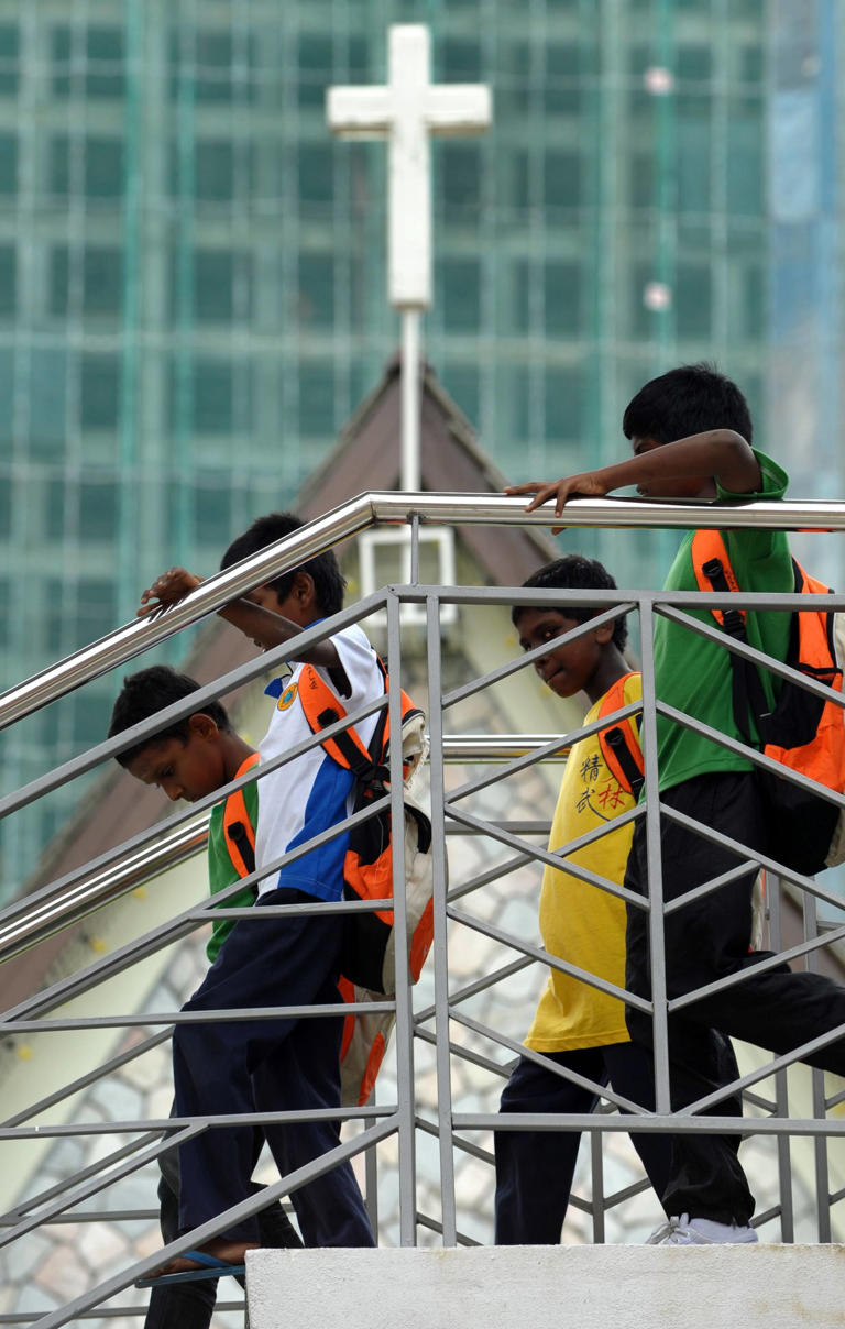 Schoolboys walk down from a bridge in front of a church in Kuala Lumpur. Photo: AFP