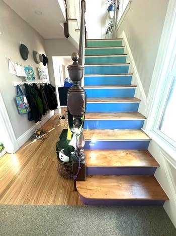 Stairway with various items on rails and steps, including coats, hats, and a helmet, suggesting a busy household entryway