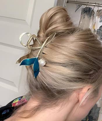 Woman with a bun adorned with a decorative hairpin featuring metallic elements and a pearl