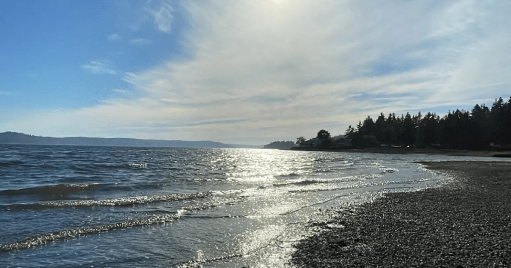 Waves slowly roll into a rocky shore in the morning at Washington State's Belfair State Park.